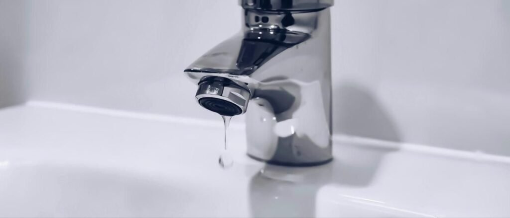 Bathroom faucet dripping into a white sink