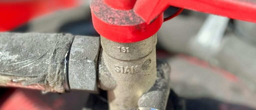 Red-handled gas shutoff valve on a supply line