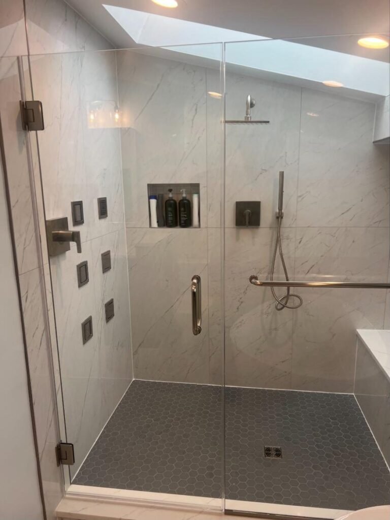 Walk-in glass shower with body sprays and a hand shower